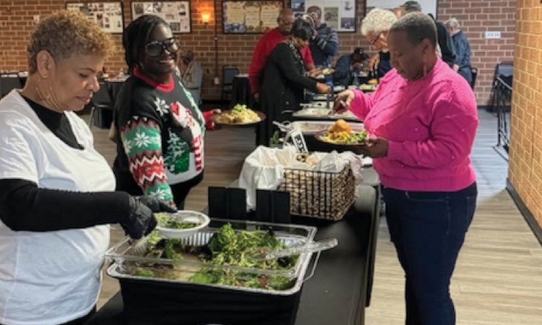 Post member Lisa Tolufashe, in holiday sweater, is served a meal at Post 7775’s holiday celebration.