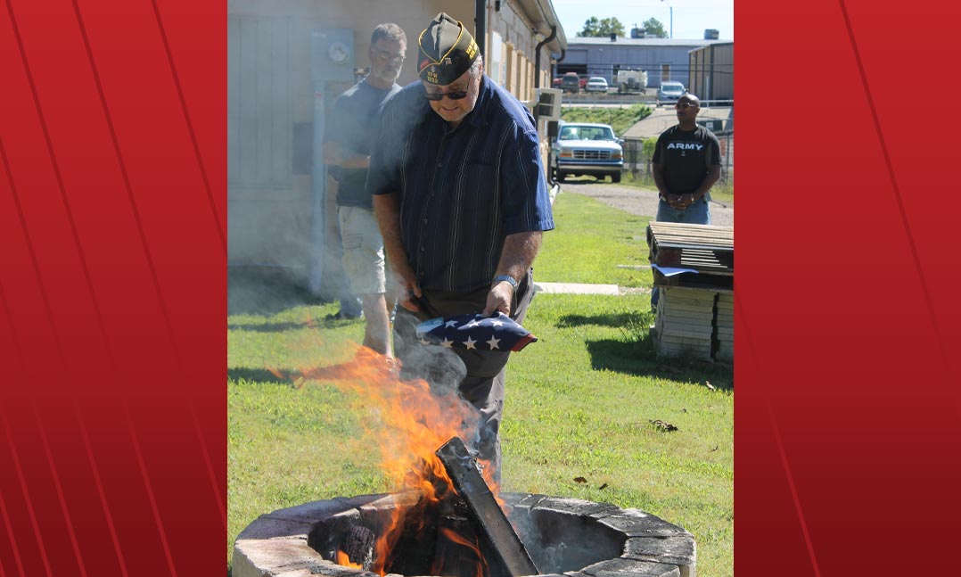VFW Post 1322 member and Navy veteran Mark Schultz retires a flag during a flag retirement ceremony