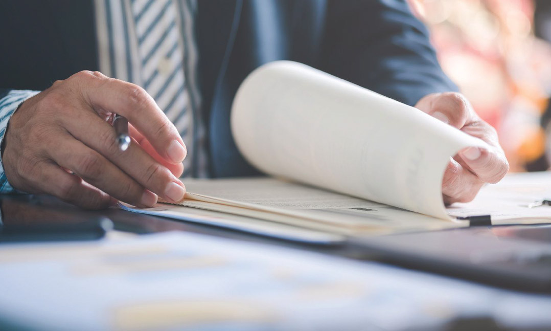 Man in a suit holding a pen looking at papers