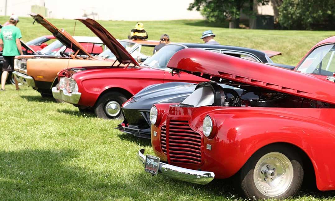 A row of vintage cars sits with their hoods propped open in June at VFW Post 7397 in Lenexa, Kansas