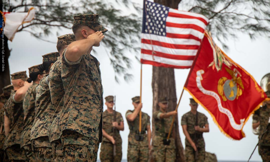 Members of the United States Marine Corps salute the US and USMC flags